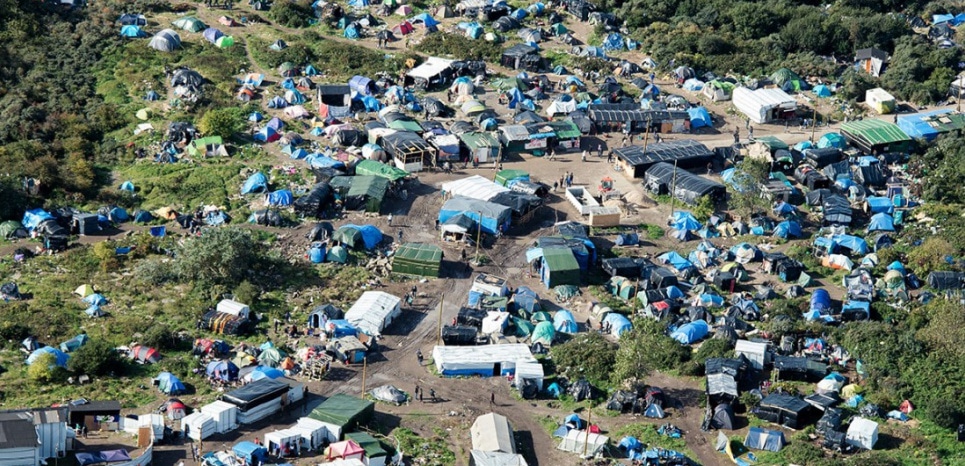 An aerial picture taken  in Calais on October 9, 2015 shows a site dubbed the "New Jungle", where some 3,000 people have set up camp -- most seeking desperately to get to England, . The slum-like migrant camp sprung up after the closure of notorious Red Cross camp Sangatte in 2002, which had become overcrowded and prone to violent riots. However migrants and refugees have kept coming and the "New Jungle" has swelled along with the numbers of those making  often deadly attempts to smuggle themselves across the Channel.  AFP PHOTO / DENIS CHARLET