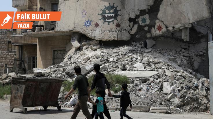 People walk past a damaged building depicting drawings alluding to the coronavirus and encouraging people to stay at home, in the rebel-held Idlib city, amid concerns about the spread of the coronavirus disease (COVID-19), Syria April 18, 2020. REUTERS/Khalil Ashawi     TPX IMAGES OF THE DAY